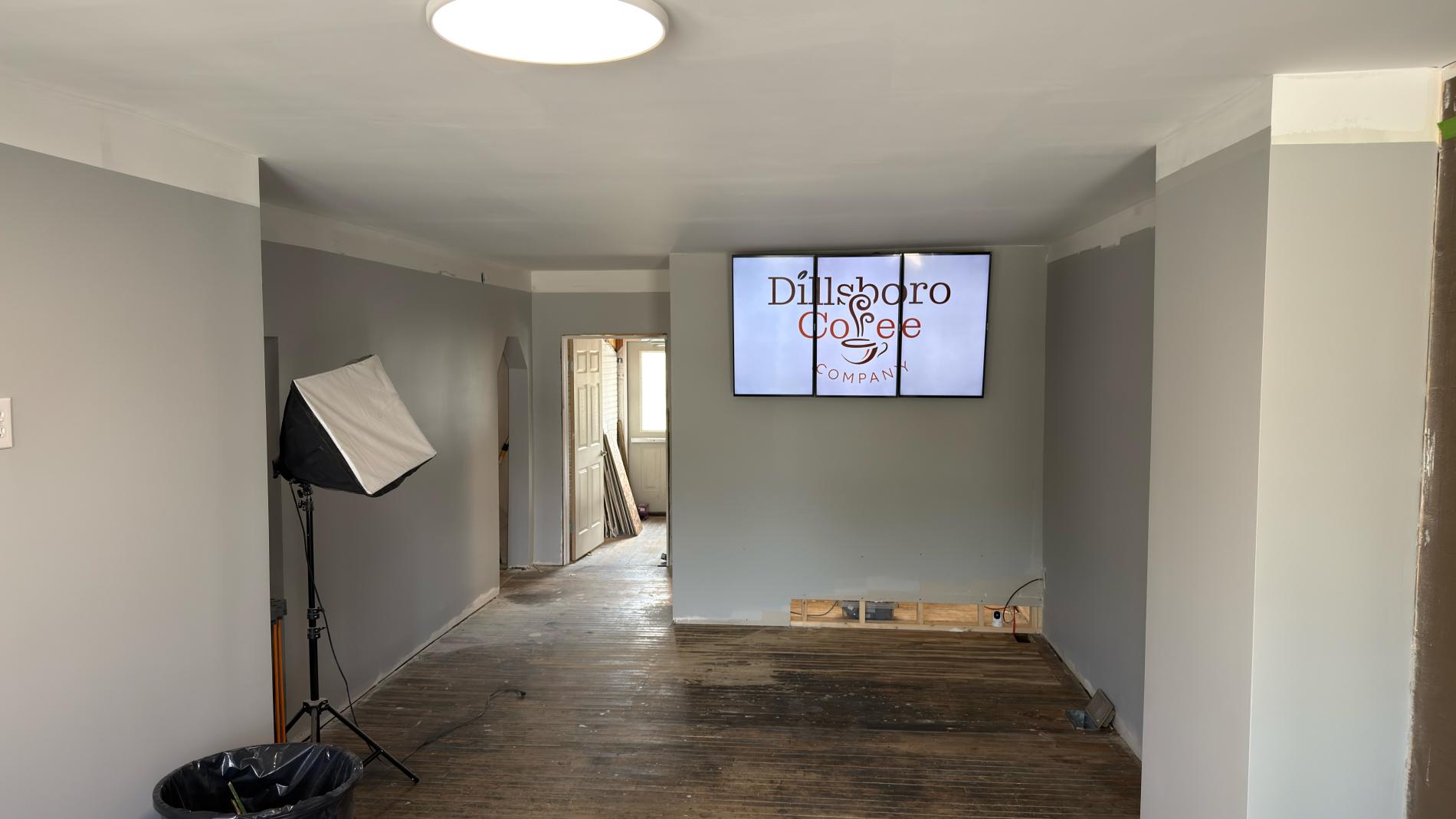 Room with gray walls, a tripod setup, and a large screen on the wall.