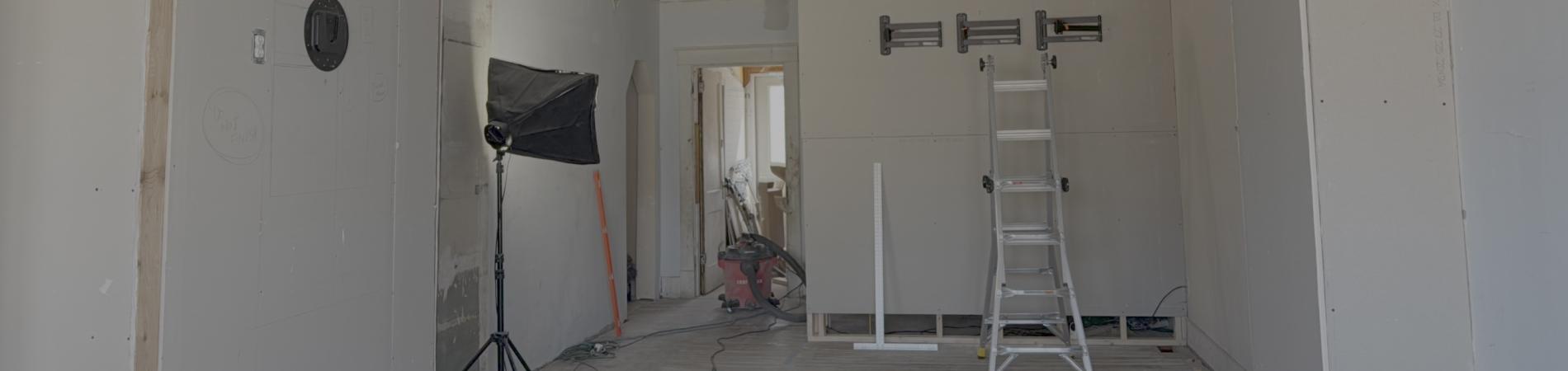 Under-construction room with ladder and drywall.