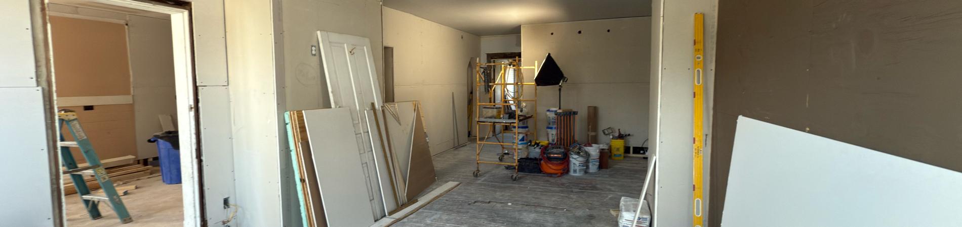 Renovation work in a large, unfurnished room with scattered tools.