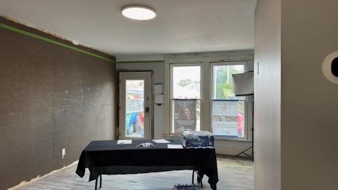 Empty room with a black table, windows, and a door.