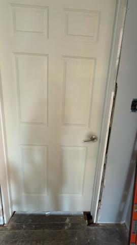 White interior door with a silver handle, surrounded by a gray wall.