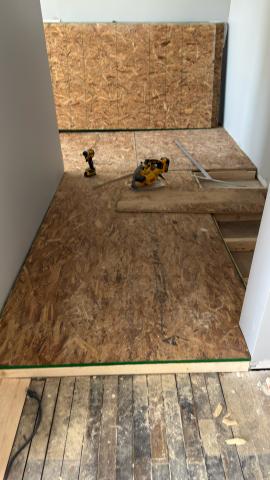 OSB flooring installation with tools in a small room.