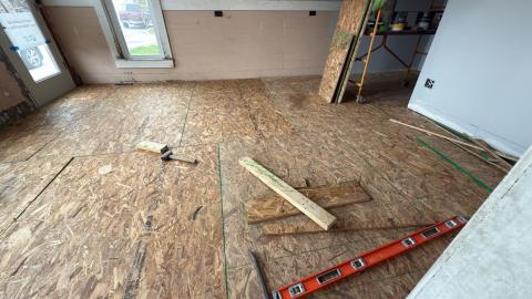 Wooden floor under construction with scattered tools and a ladder.